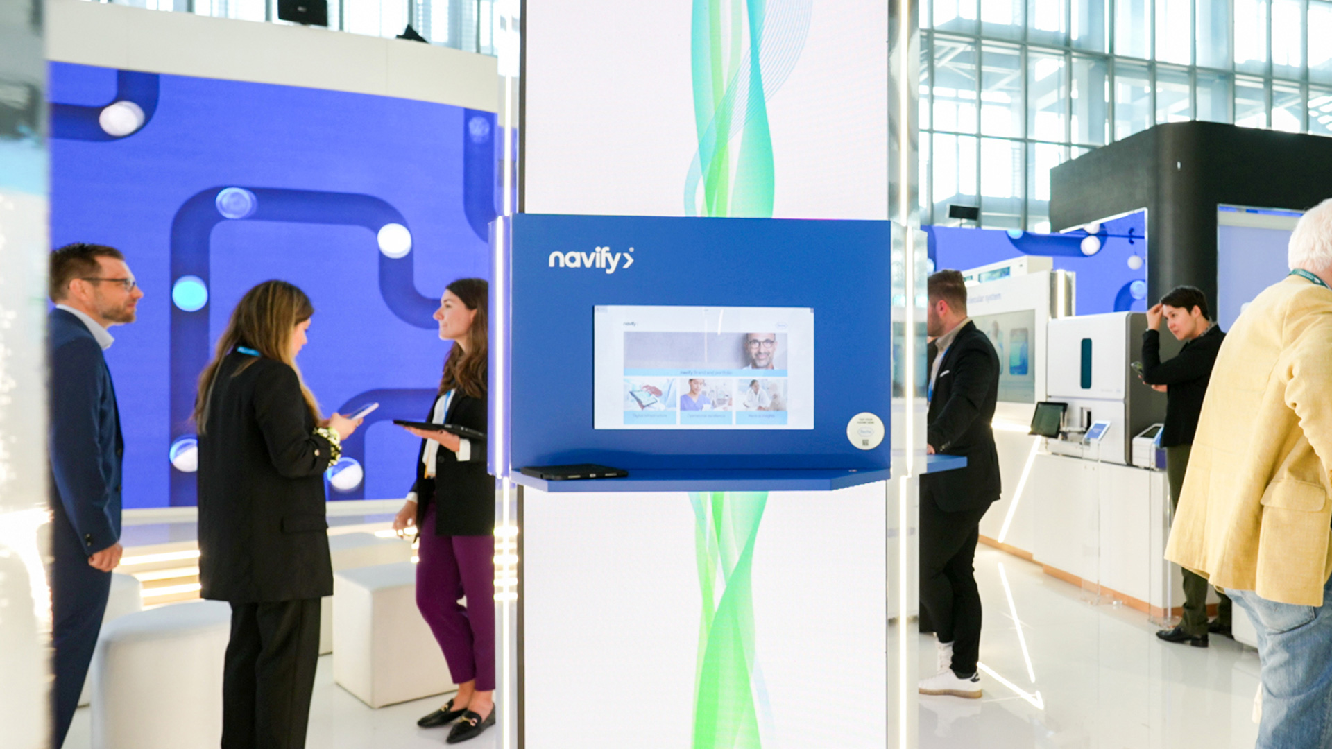 Visitors exploring the navify digital solutions station inside the Roche booth.
