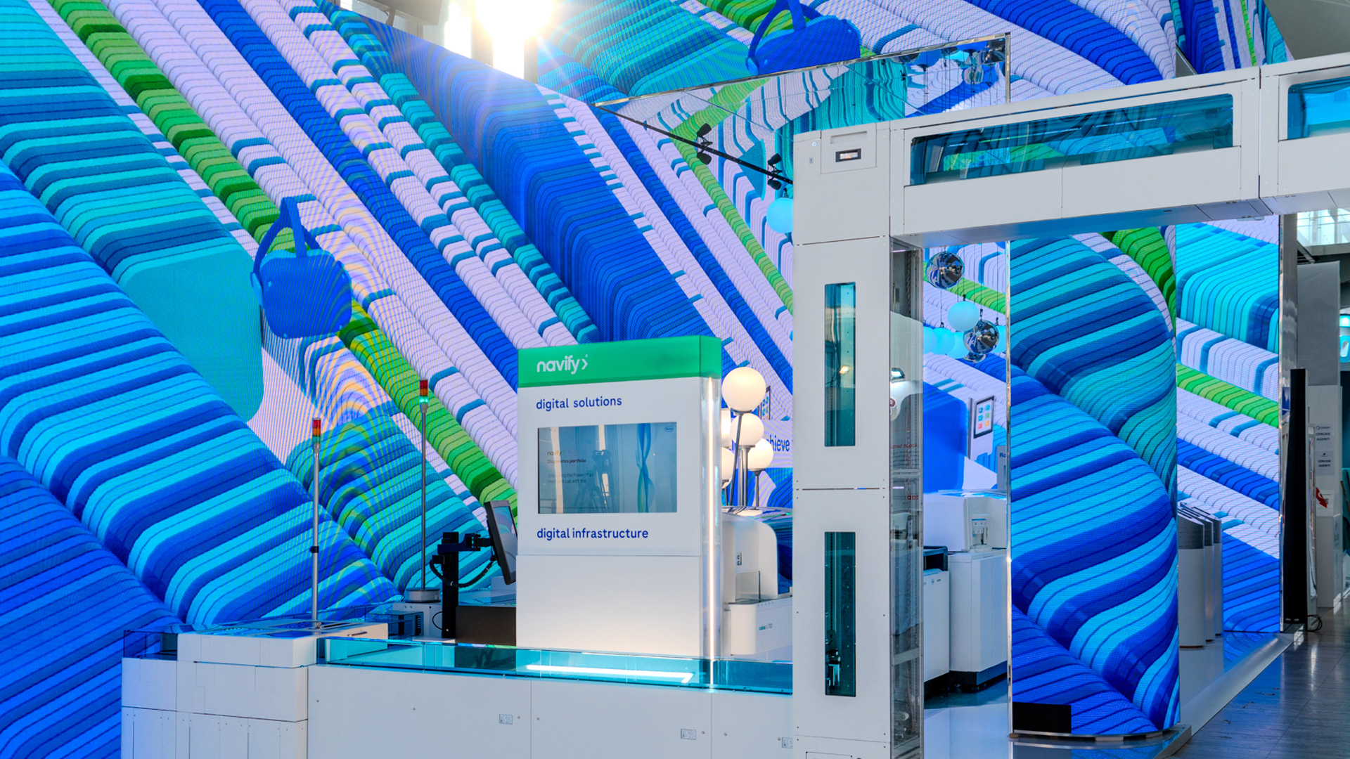 Diagnostic instruments displayed beside immersive digital walls inside the Roche booth at EML Rome.